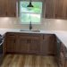 Kitchen remodel by DreamMaker in Central Texas featuring white marble countertops, sleek wooden cabinetry & large sink.