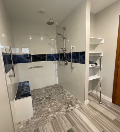 A modern ADA-compliant walk-in shower featuring a tiled bench, dual showerheads, grab bars, and striking dark blue accent tiles.